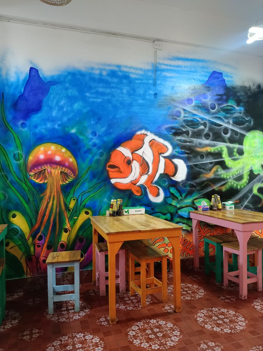Inside Somtam Tid Zaeb restaurant interior with colorful mural